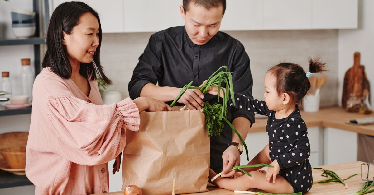 A Canadian family reviewing a grocery list and weekly meal plan on a kitchen table.